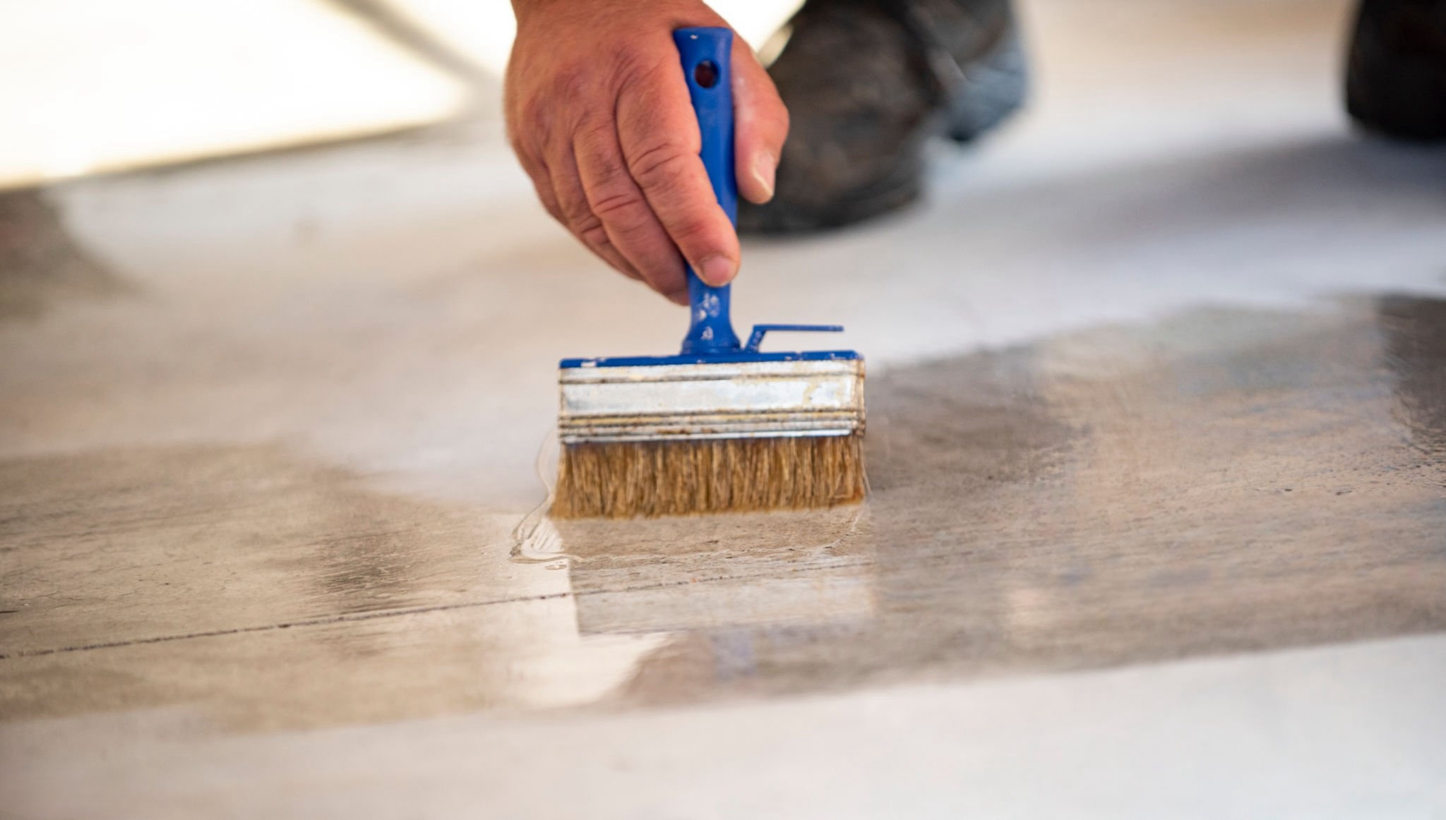 Manual worker painting concrete floor for protection